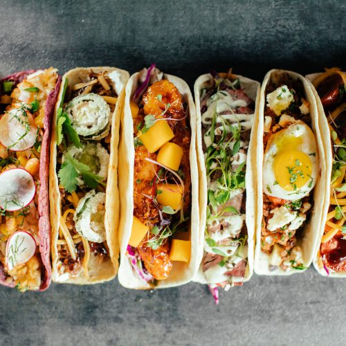 Close up of eight tacos in a row
